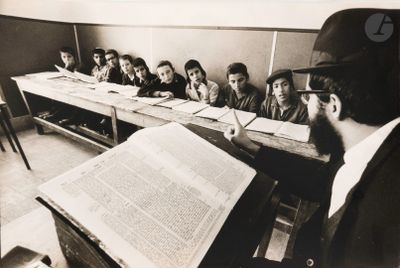 black and white photograph of a man reading a book in a classroom