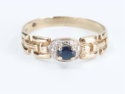 a close up of a gold ring with a sapphire and diamonds