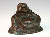 statue en bronze représentant un Bouddha souriant assis sur un socle blanc