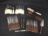 many different types of knives and spoons laid out on a table
