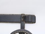 a leather belt with a metal buckle hanging on a wall