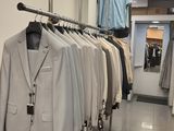 many suits hanging on a rack in a clothing store