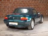 a blue convertible car parked in front of a brick wall