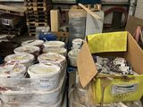 de nombreux seaux de peinture posés sur des palettes dans un entrepôt