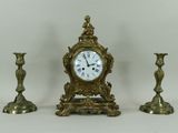 trois bougies et une horloge posées sur une table