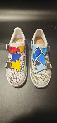 une paire de chaussures pour enfants ornées de motifs colorés, posées sur une surface noire