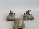 four toy tanks that are sitting on a white surface