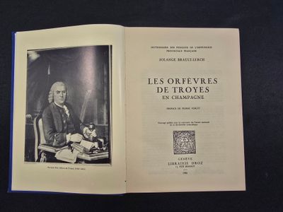 un livre ouvert sur lequel figure l'image d'un homme assis à un bureau