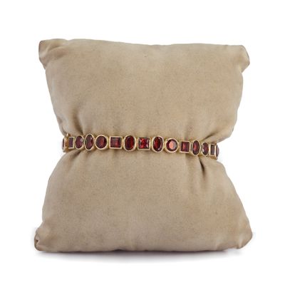 un coussin beige orné d'un oreiller et d'un bracelet doré