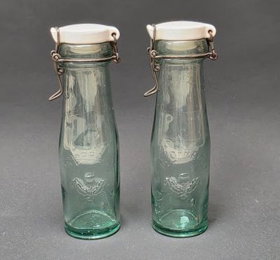 paire de salières et poivrières en verre vert avec des couvercles blancs