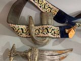two knives and a belt are on display on a table