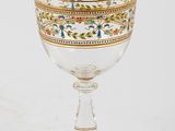 an antique glass goblet with a gold rim on a white background
