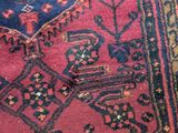 a close up of a red rug with a blue and green design