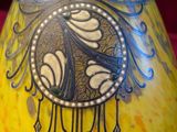 a yellow vase with a black and white design on it