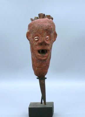 sculpture représentant une tête d'homme posée sur un socle en bois, sur fond blanc