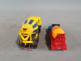 two toy trains sitting next to each other on the ground