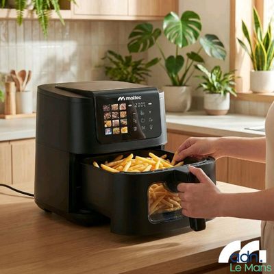 une femme en train de mettre des frites dans une friteuse à air chaud posée sur un plan de travail de cuisine