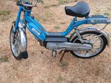 un scooter bleu garé dans l'herbe