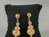 un gros plan sur une paire de boucles d'oreilles posées sur un oreiller
