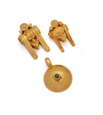 three pieces of gold jewelry on a white surface with a green stone