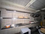 une petite cuisine équipée d'un micro-ondes et de casseroles et poêles accrochées au mur