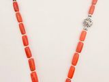 a necklace with coral beads and silver accents on a white background