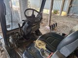 une photo d'un tracteur garé sur un terrain en terre battue