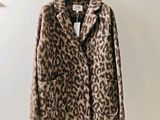 a leopard print coat hangs on a hanger in a room
