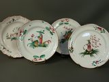 quatre assiettes blanches ornées de motifs rouges et verts, posées sur une table