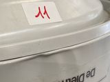 a white trash can with a red sticker on it