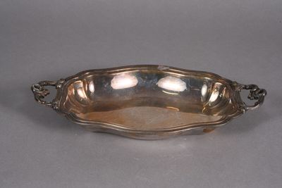 an antique silver plate with a handle and handles on a gray surface