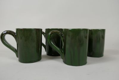 quatre tasses à café vertes sont alignées sur une surface blanche