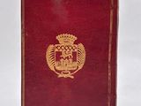 an old red book with a gold emblem on the cover
