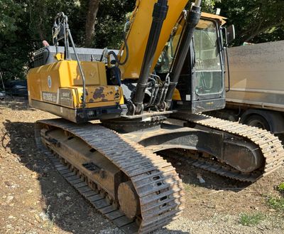 une photo d'une pelleteuse jaune et noire sur un terrain en terre battue