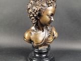 bronze bust of a woman with curly hair on a marble base