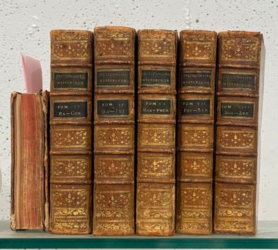 many old books sitting on a shelf next to each other