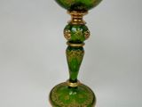 a green glass with a gold decoration on it
