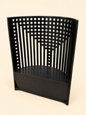 une photo d'une chaise noire avec un panier accroché au dossier