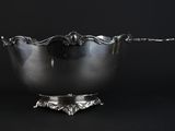 a silver bowl with a spoon in it on a black background