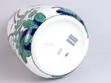 a white vase with blue and green flowers on it