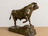 bronze statue of a bull on a rock on a table