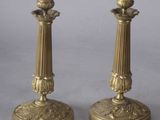 pair of antique brass candlesticks on pedestals on grey background