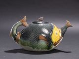 a teapot shaped like a fish with a yellow fin