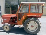 un petit tracteur orange garé devant un bâtiment