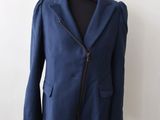a blue jacket on a mannequin stand against a white wall