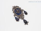 an image of a blue and silver broochle with a flower on it