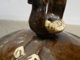 a brown vase with a bird sitting on top of it