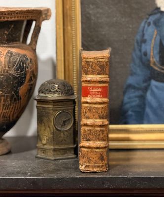 une photo représentant un vase, un livre et une bougie posés sur une étagère