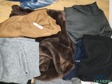 a pile of clothes on the floor next to a bottle of water
