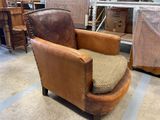 a brown leather chair with a tan cushion on it